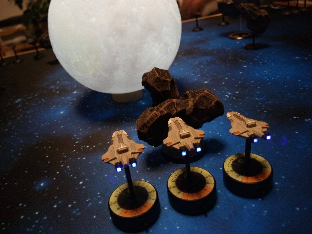 Full Thrust LED powered cruisers of the Star Alliance hiding behind asteroids and the moon.